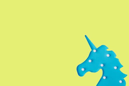 Blue unicorn on yellow backdrop. Festive concept. Flat lay style.