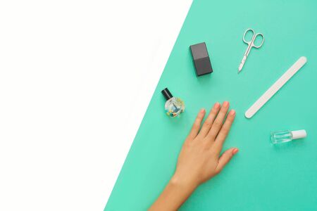 Beautifully manicured orange nails on the mint background with tools for manicure. Flat lay. Place for text.の写真素材