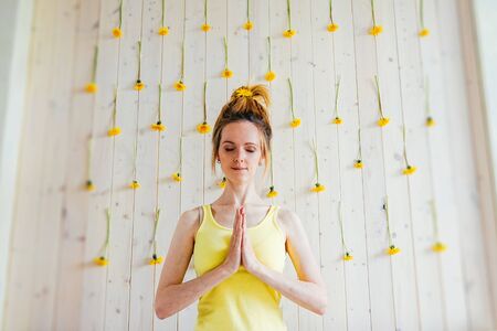 Woman with close eyes and namaste and wall with yellow dandelions. Fashion happy concept.の写真素材