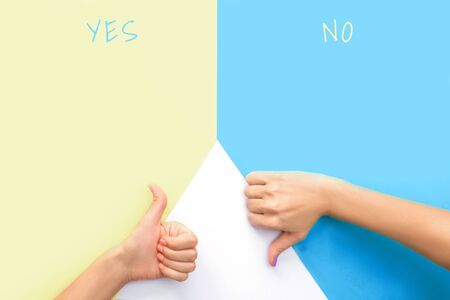 Yes or no concept. Yellow and blue backgrounds. Bright trendy female manicure. Woman's hands with orange and violet manicure.の写真素材