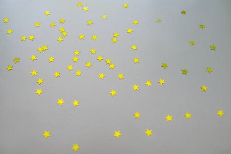Golden stars on a silver background. Christmas and New Year background of golden confetti stars.