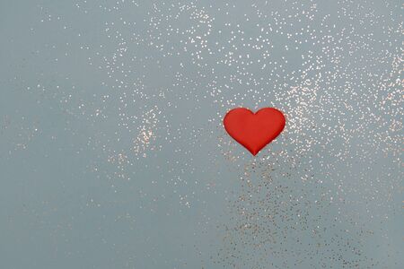 Red heart on a blue background with sparkles. Copy space, top view. Valentines day concept.の写真素材
