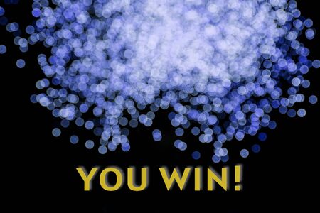 Blue shiny background of sparkles bokeh on black. Lettering You Win.の写真素材