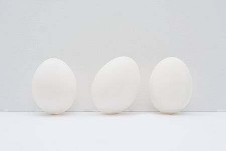 Three easter white eggs on light background.の写真素材