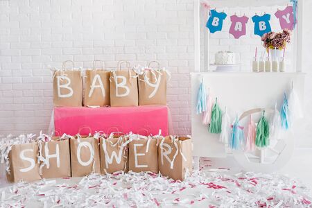 Decoration for baby shower with candy bar. White brick wall on background. Paper show.