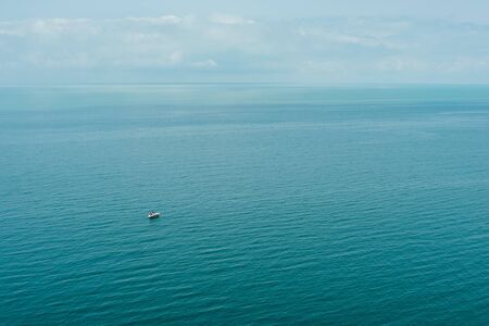 Blue sea waves soft surface with little ship. Summer abstract background patternの写真素材