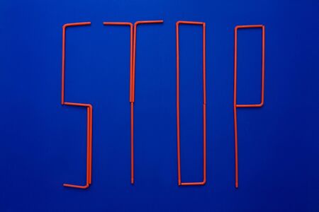 Word of stop from disposable tubes on blue background. Ocean pollution symbol.の写真素材