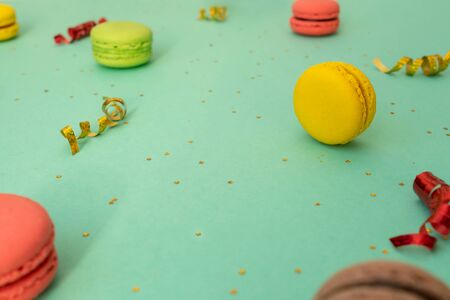 Sweet and colourful french macaroons on turquoise background with festive serpentine. Copy space.の写真素材