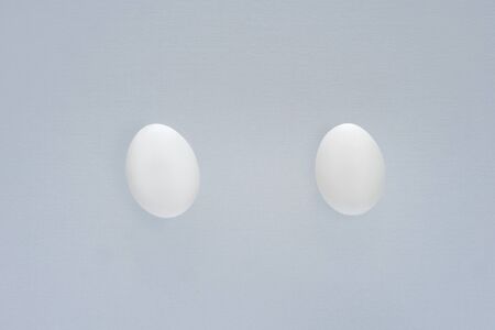 Flying two easter white eggs on light background. Minimal concept.