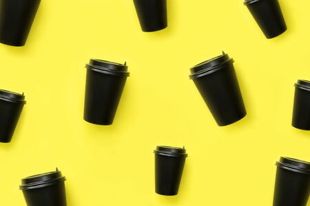A pattern from a disposable coffee cup on a yellow background. Black craft glass for coffee or tea.の写真素材