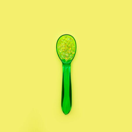 Vitamin d gel capsules in green spoon on yellow background. Copy space.の写真素材
