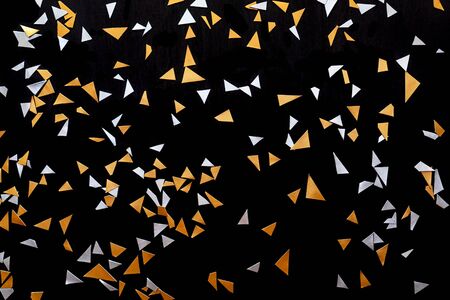 Golden and silver triangle confetti isolated on black background.の写真素材