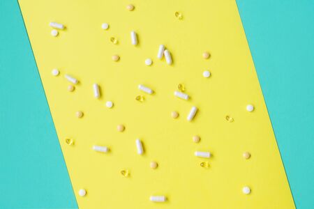 Pills capsules on yellow and turquoise. Flat lay.の写真素材