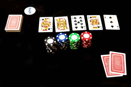 Two cards, stack and chips, poker game. Black background, copy space.