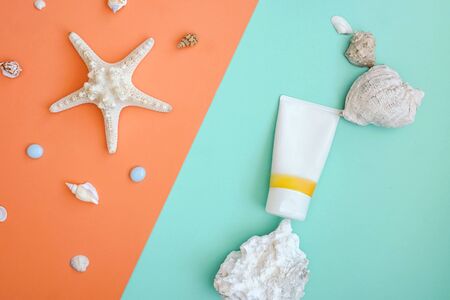 Sunscreen as part of natural composition from shell, stone. Flat lay on turquoise and orange, balance, zero gravity. Sustainable design.の写真素材