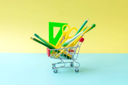 Green yellow stationery in food basket on turquoise and yellow. Hipster minimal concept. Front view.の写真素材