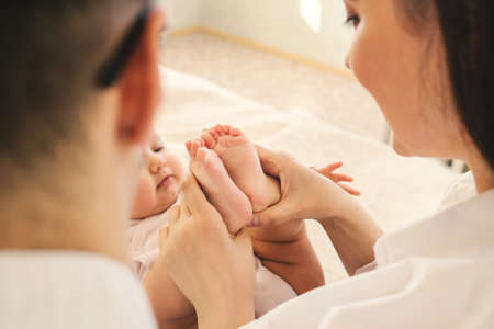Mom and Dad hold baby legs. Taking care of a newborn.