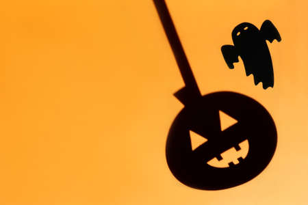 Flat lay Halloween background with decorative pumpkin and ghost on orange backdrop. Festive concept.