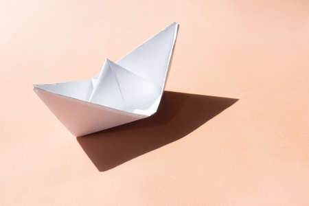 paper ship with shadow on sand color backgroundの写真素材
