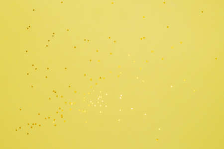 Yellow stars on a yelow background. Festive background of gold confetti stars.