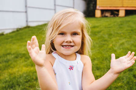 Happy childhood: Little girl having fun on grass. Close up portrait of little beautiful girl.