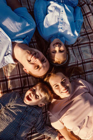 Happy family have a rest together in a picnic outdoors. Blue pink clothes, casual. Beautiful mother, father and children, top view.の写真素材