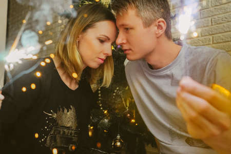 Family couple with sparklers and Christmas tree.