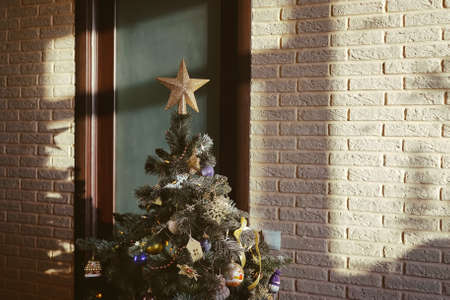 Luxury living room interior with decorated chic Christmas tree, light and shadow on brick wall.
