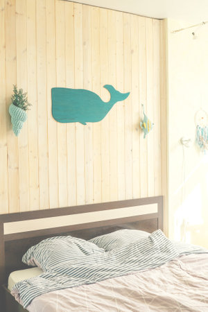 Interior of the bedroom in a marine theme with wooden wall, whale and knitted shell on wall.の写真素材