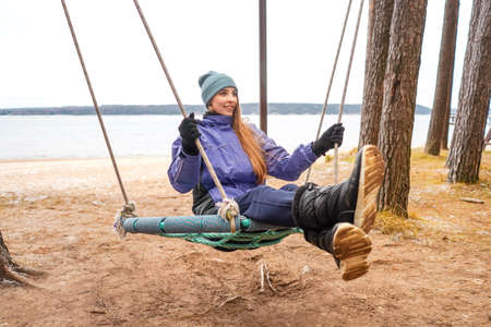 Smiling woman on Swing. River on background, autumn nature and calm. Self isolation.の写真素材