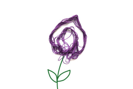 Purple flower made of thread on white background. Stem and leaves painted. Copy space.の写真素材