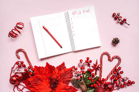 Wish list of presents text on notebook, christmas concept. Red baubles on pink background as decorations.の写真素材