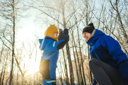 Active father and son playing and throw snow in winter park, sunny day. Happiness in moment, emotions.の写真素材