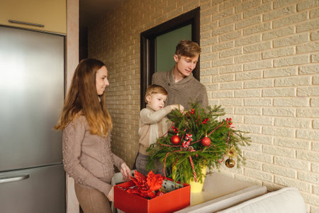 Happy family decorating a fir branches like Christmas tree with boubles in the living-room.の写真素材