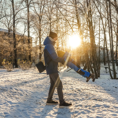 Father circling son in winter park, sunny day. Happiness in moment, emotions. Sun on background.の写真素材