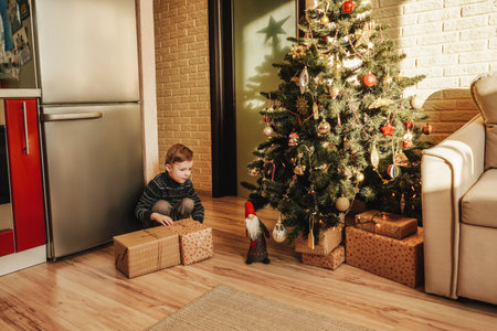 Little boy takes gifts from under Christmas tree. New Years and Christmas concept.の写真素材