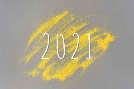 Inscription 2021 on a gray background with yellow sparkles. Festive Christmas and New Year concept.