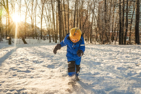 boy kicking snow in Winter, park. Sunny day.の写真素材