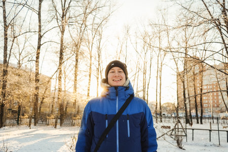 Happy man in winter park. Sunny day, blue jacket.の写真素材