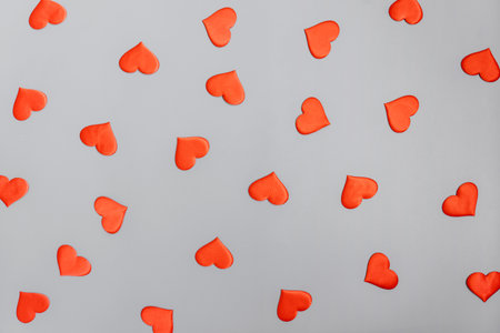 Red hearts pattern on a gray background. Copy space. Flat lay.