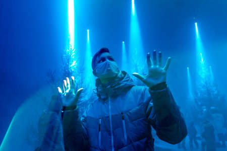 Coronavirus Covid-19 concept. Neon light barrier. Stay at home concept. Man wearing mask for protect. Social distancing concept.の写真素材