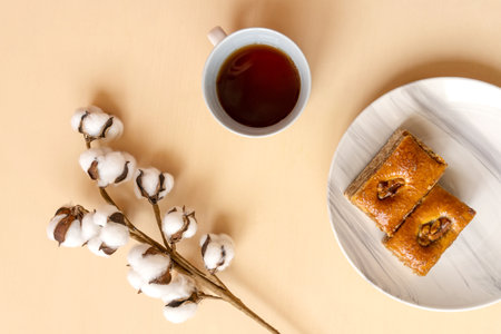 Perfect breakfast: baklava on marble plate and cup of black tea. Flat lay with cotton plant.の写真素材