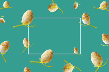 Spring pattern with flying yellow eggs on turquoise background. Zero gravity concept. Hello spring, frame for text.の写真素材