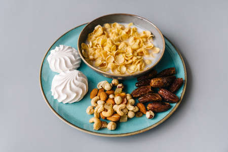Bright breakfast on gray background, front view. Tasty flackes, nuts, marshmallows and dates.の写真素材