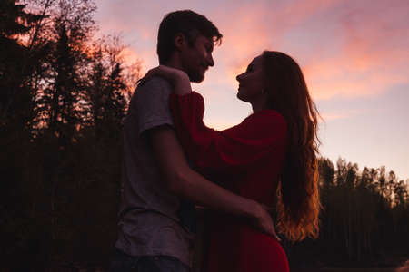 Man and woman silhouettes on pink sunset sky background. Valentine day concept.の写真素材