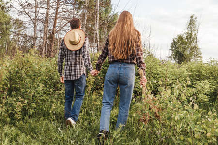 A couple in love between bushes. Back view, bouquet of spikes. Man with hat.の写真素材