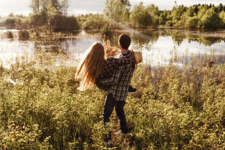 A couple in love in the field near lake. Woman riding a man, funny play.の写真素材