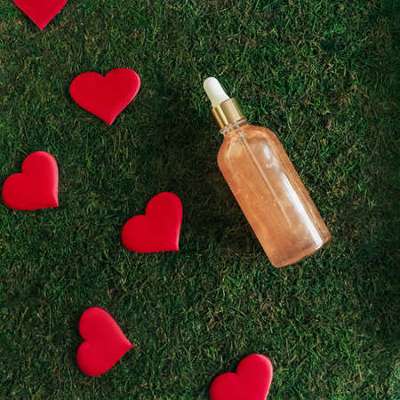 top view of bottle with face serum in green moss. Red hearts as decoration.の写真素材