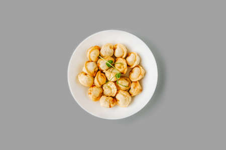 Fried dumplings on a white plate on gray background. Russian food. Top view, isolated.
