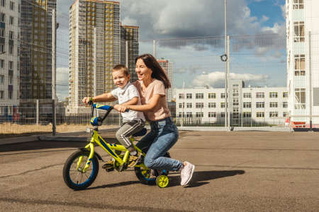 Boy rides a bike with his mother.